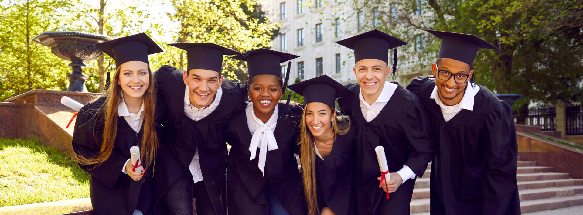 Group Of Happy Diverse University Students In Caps And Gowns Hugging And Smiling Group Of Happy Diverse University Students In Caps And Gowns Hugging And Smiling